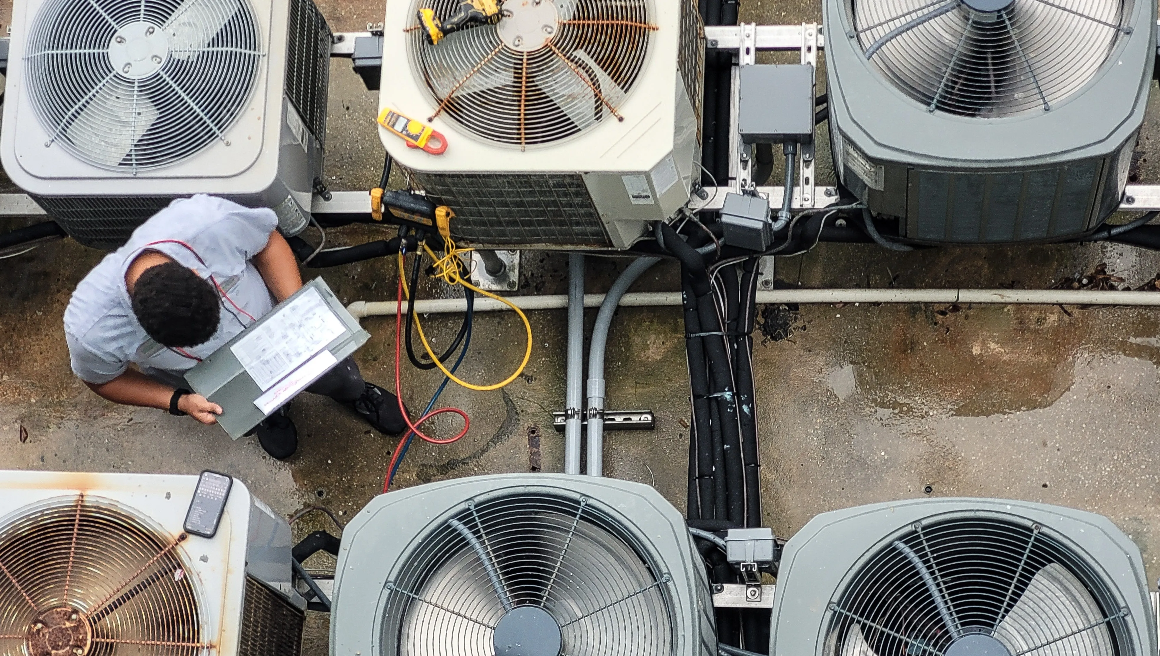 Technician servicing rooftop HVAC condenser units